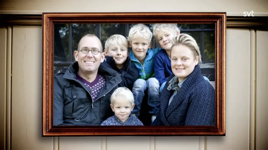 Stiligt - Ett inramat foto av två vuxna och fyra små barn som alla sitter tillsammans och ler mot kameran.
