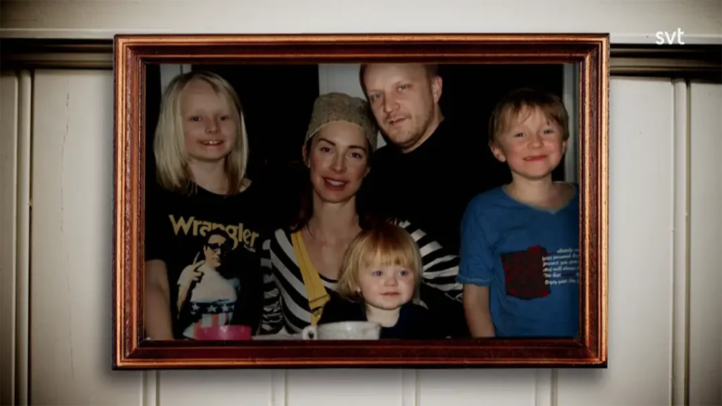 Stiligt - Ett inramat foto av två vuxna och tre barn, alla ler och poserar tillsammans inomhus.