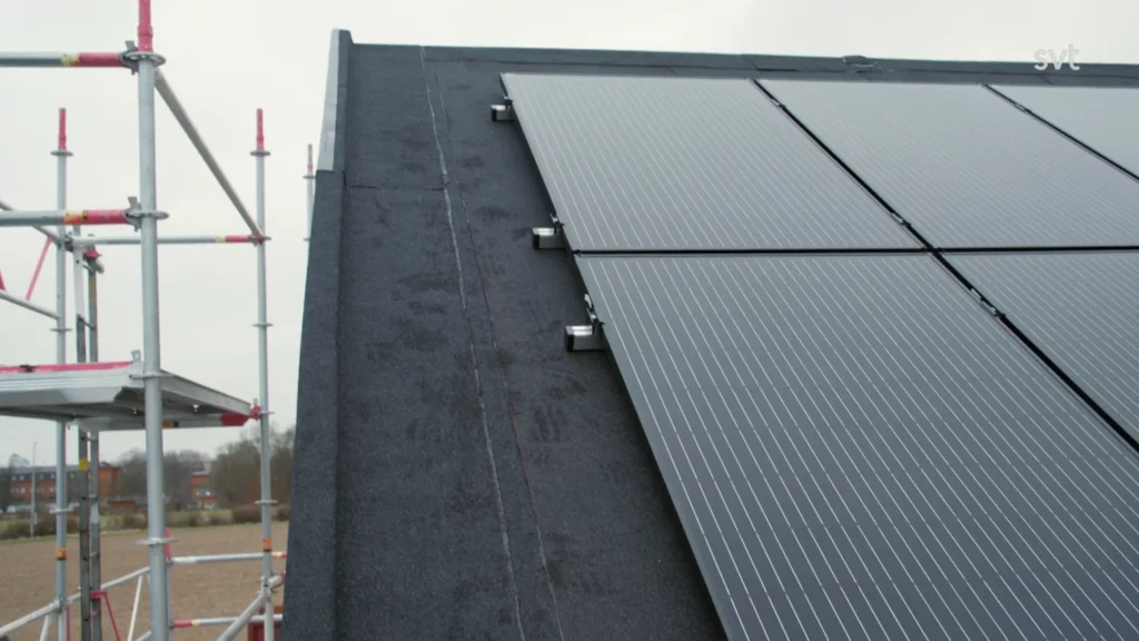 Stiligt - Närbild av solpaneler installerade på ett sluttande tak, med ställningar synliga på vänster sida av bilden.