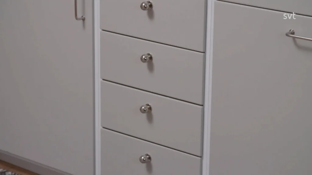 Stiligt - En närbild av fem stängda grå lådor med runda metallhandtag, placerade i ett skåp.