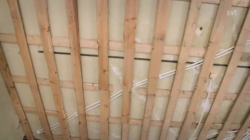 Stiligt - Frilagd trätakram med synlig isolering, elektriska ledningar och plastduk.