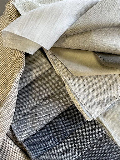 Stiligt - Ett urval av tygprover i neutrala nyanser av beige, grått och taupe, arrangerade i överlappande lager.