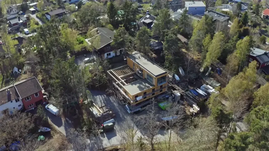 Stiligt - Flygfoto över ett modernt hus under konstruktion omgivet av träd och närliggande hus i ett bostadsområde.