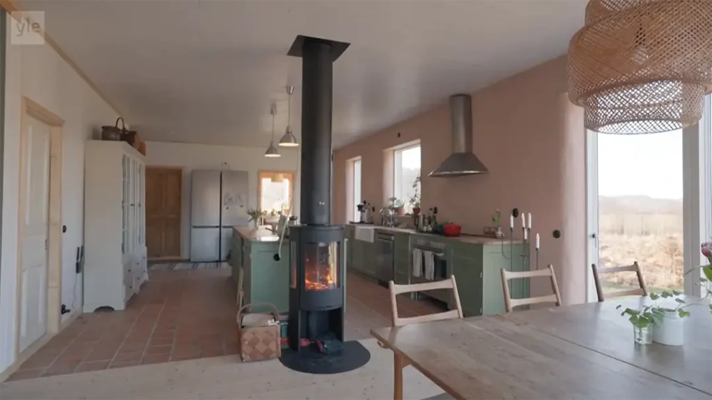 Stiligt - Ett modernt kök och matplats i öppen planlösning med gröna skåp, en braskamin, stora fönster och naturligt ljus.