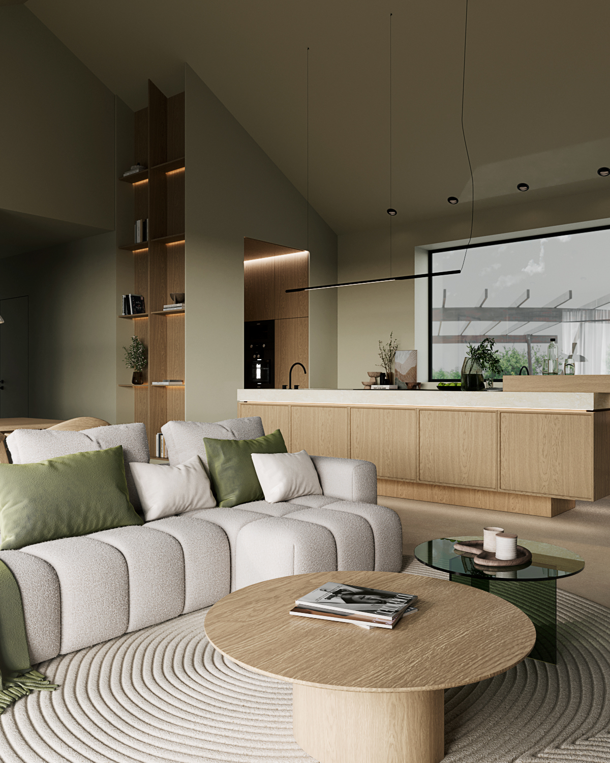 Stiligt - Ett modernt vardagsrum med en stiligt ljusgrå soffa med gröna kuddar, kompletterat med ett runt soffbord i trä. Det rymliga köket smälter samman sömlöst, och de minimalistiska väggarna och hyllorna är värda för dekorativa växter, vilket bibehåller ett öppet och elegant utrymme.