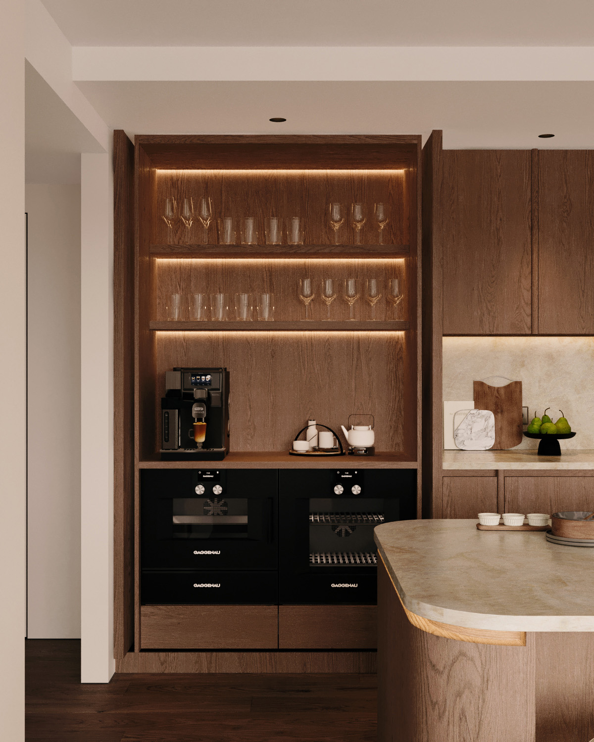 Stiligt - exklusivt kök med rundade former, stiligt träskåp, upplysta glashyllor med glas, en snygg kaffemaskin och inbyggda ugnar. Den marmortoppade ön i förgrunden har en snygg skärbräda och skål i trä.