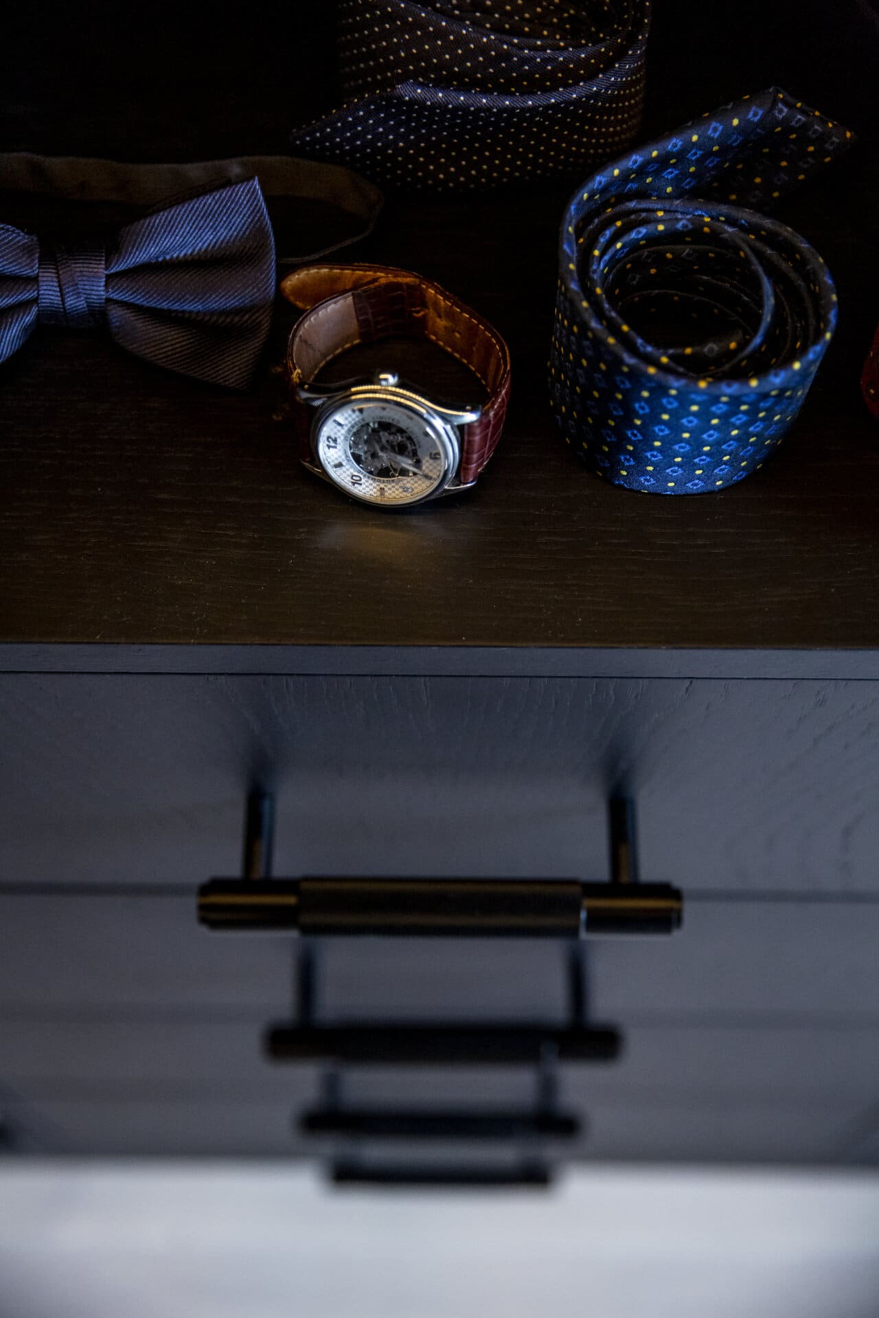 Stiligt -Svart Walk in closet  En stiligt låda med ett armbandsur, snyggt rullade slipsar och en elegant fluga till vänster.