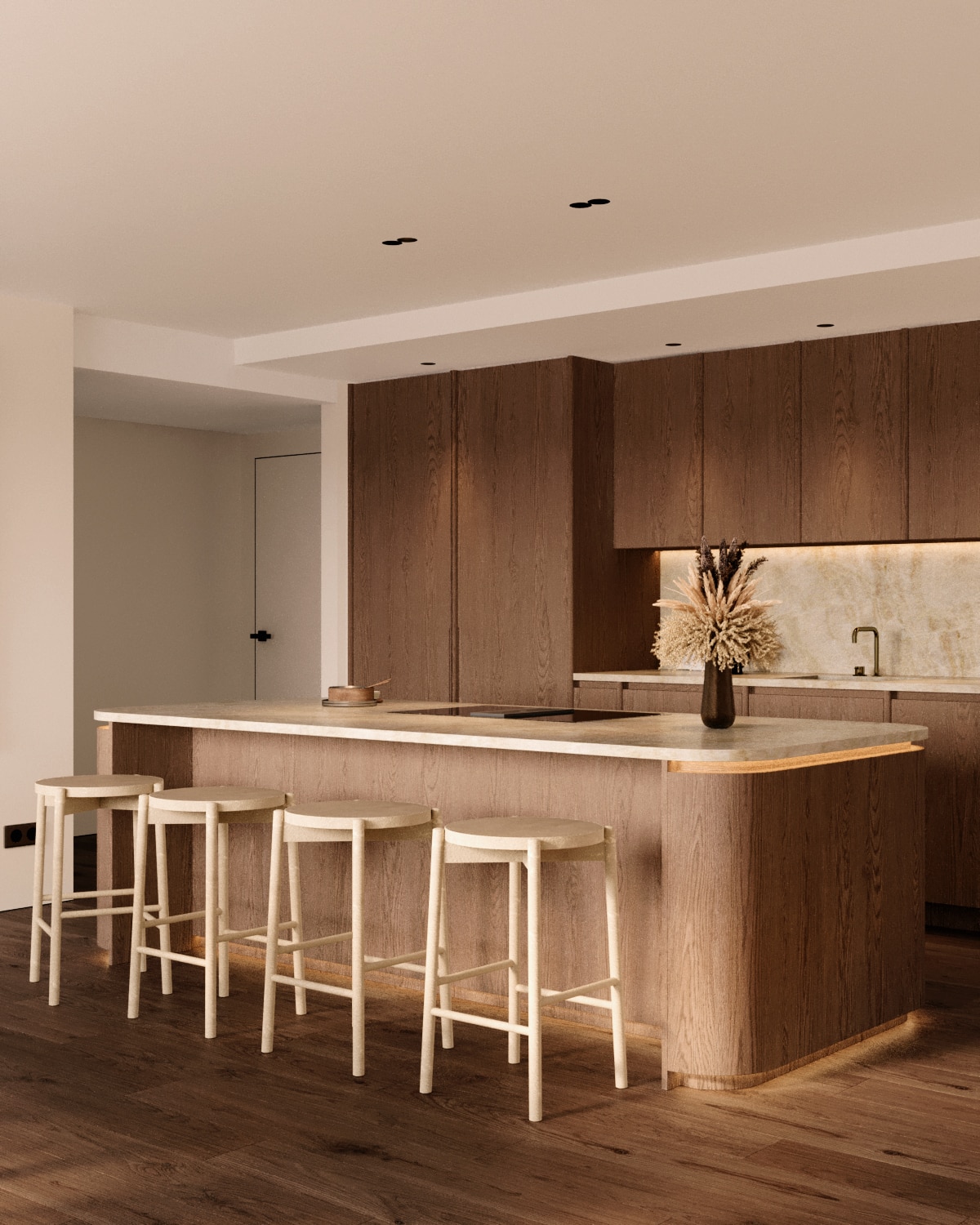 Stiligt - Modernt platsbyggt kök med träskåp, en stor ö med beige bänkskiva, fyra ljusa träpallar och en vas med torkade växter på ön.