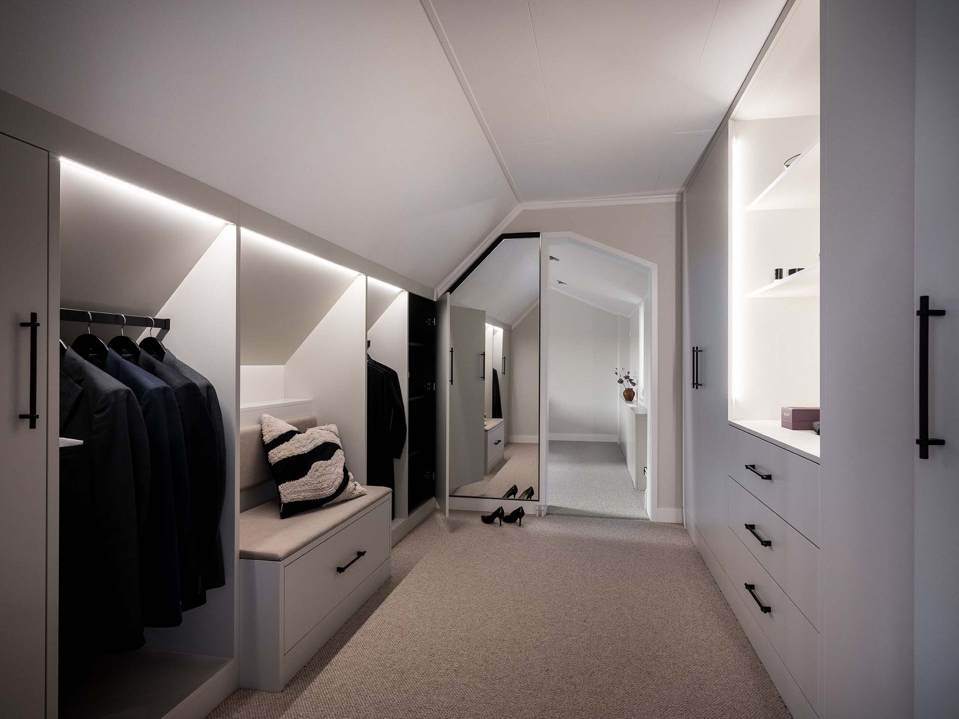 Stiligt - Modernt ljus walk in closet med inbyggda garderober, hängdräkter, dämpad bänk, öppna hyllor och en stor golvspegel i slutet.