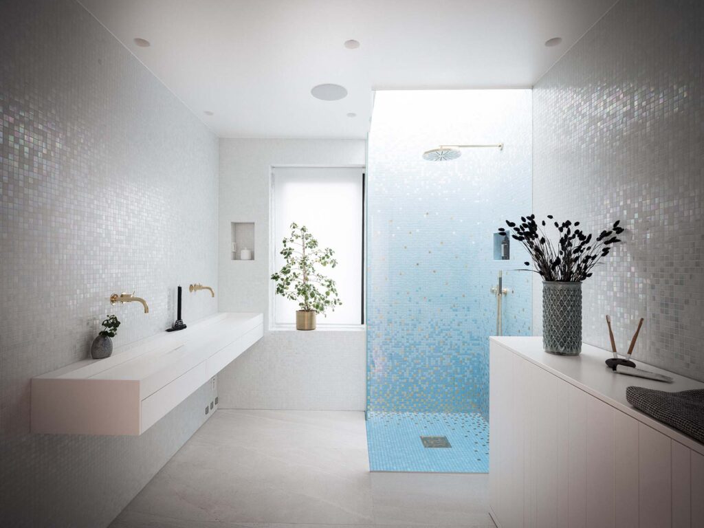 Stiligt - Modernt badrum med vita mosaikplattor, svävande dubbelt handfat, glasdusch med blått klinkergolv, krukväxter och minimalistisk inredning.