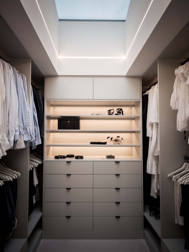 Stiligt - En modern klädkammare med mycket förvaring, med hängande kläder på båda sidor, hyllor för accessoarer och skor och ett takfönster ovanför för naturligt ljus.