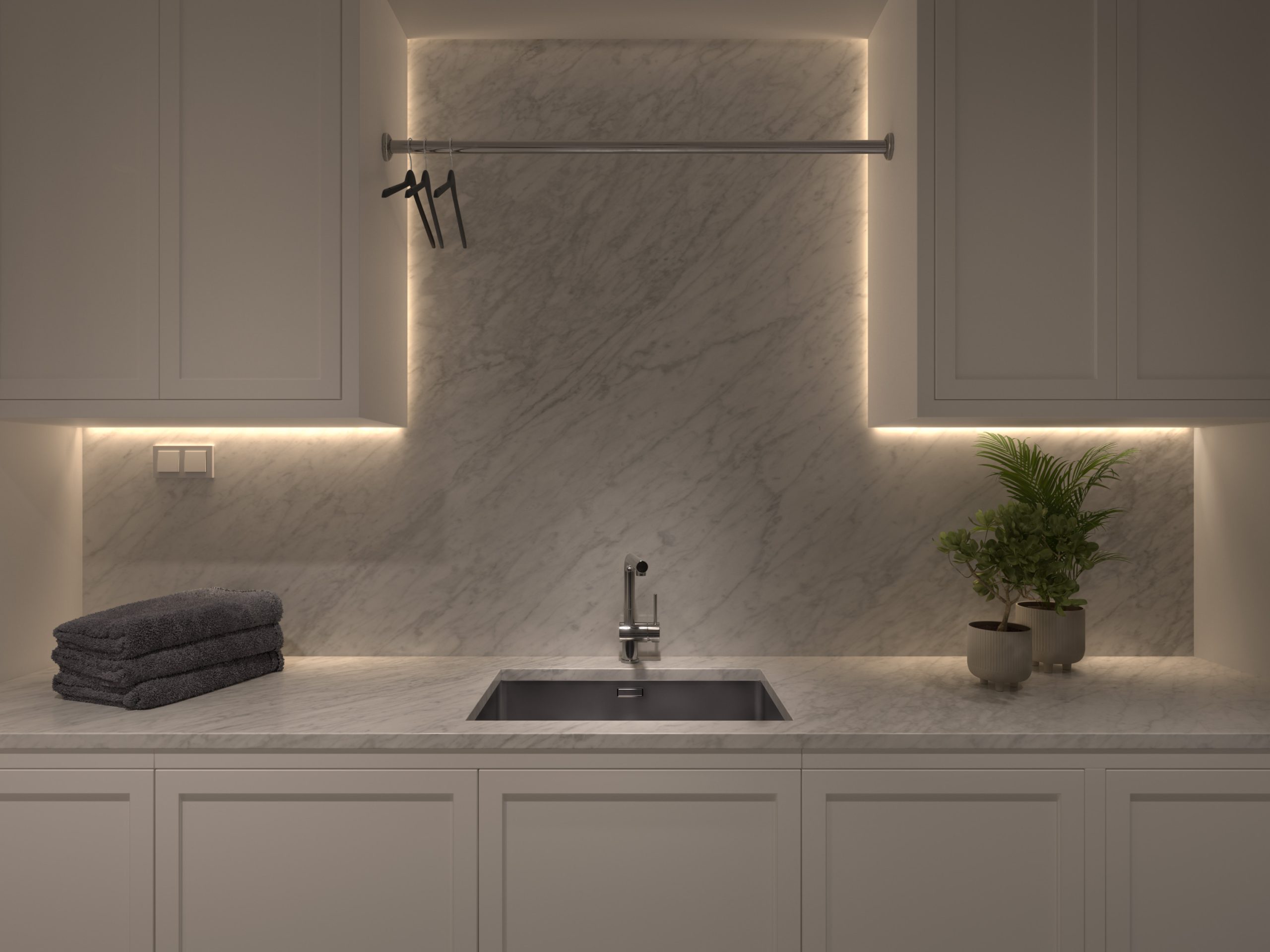Stiligt - Modernt kök med backsplash i marmor, belysning under skåpet, diskbänk i rostfritt stål, vikta handdukar och två krukväxter – perfekt inspiration för en modern tvättstuga.