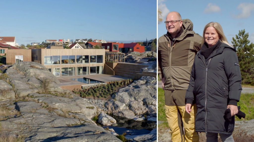 Stiligt - Ett modernt kusthus med stora fönster ligger på stenig terräng; bredvid står en man och en kvinna i friluftsjackor utanför och ler.