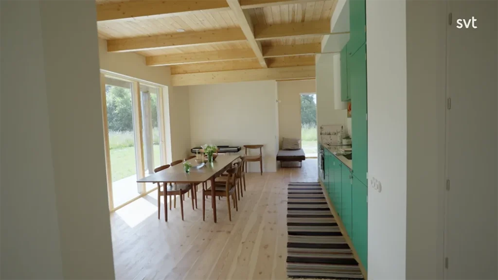 Stiligt - En ljus, minimalistisk matplats med trägolv, gröna köksskåp och stora fönster med utsikt över en gräsbevuxen utomhusscen som fångar den luftiga elegansen i Sandby - Husdrömmar stil.