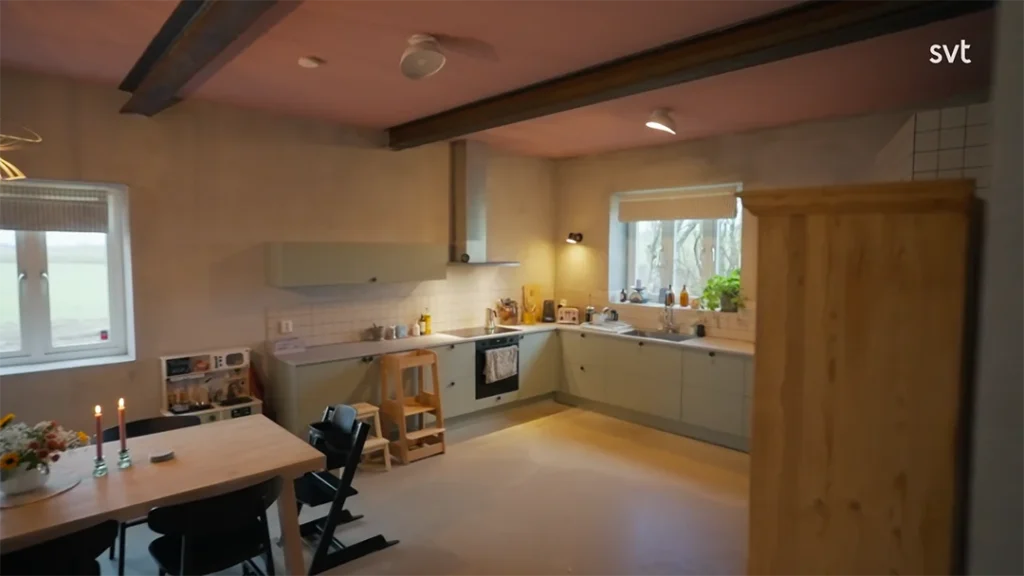 Stiligt - Modernt kök med ljusgrå skåp, matbord i trä med stolar och naturligt ljus som strömmar genom fönstret. Ett Kverrestads träskåp står nära matplatsen.